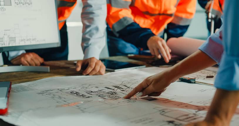 Closeup of team of industrial engineers meeting analyze machinery blueprints consult project on table in manufacturing factory. Working in manufacturing plant or production plant concept.